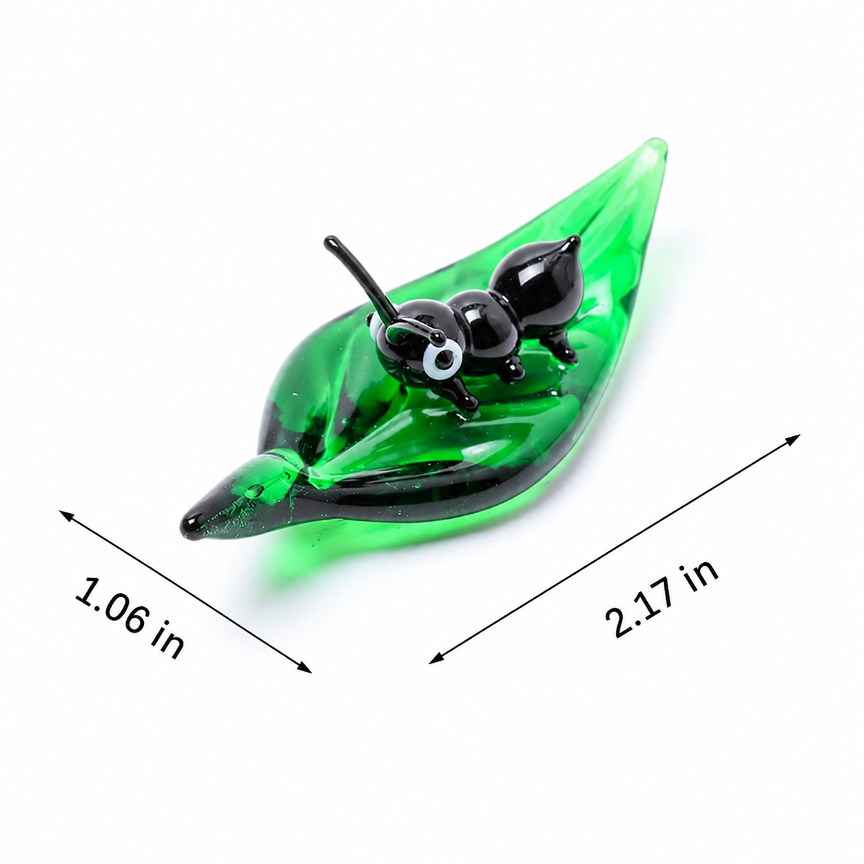 A green leaf-shaped glass candle holder with a black ant figure on top, shown on a white background with dimension arrows and labels indicating 1.06 in by 2.